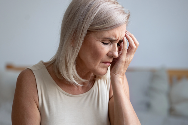 closeup tired aged woman touches face with hand