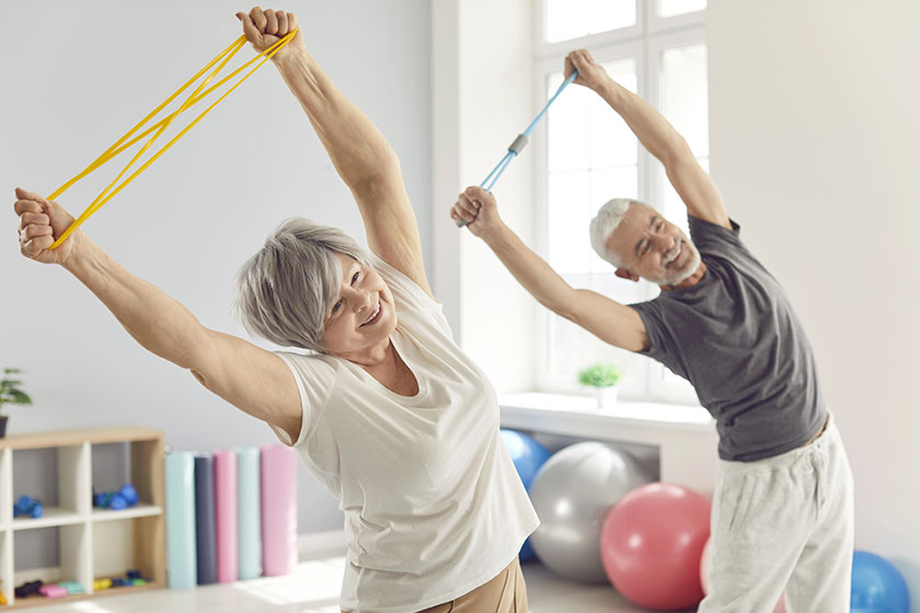 Smiling mature senior man woman doing stretching exercises rubber band Smiling mature senior man woman doing stretching exercises rubber band