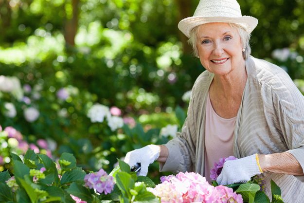 woman smiling looking ahead while pruning flowers