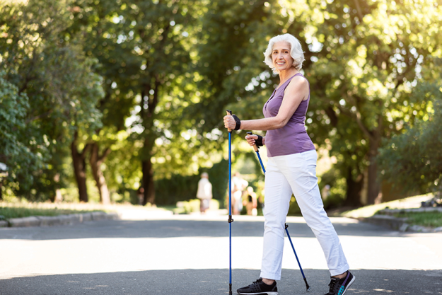 grey haired woman walking with tracking sticks