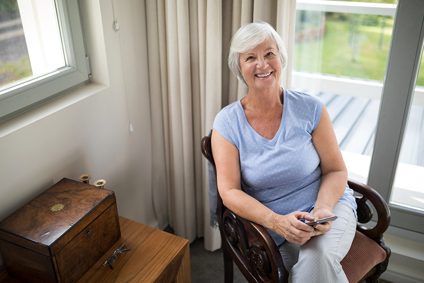 senior woman sitting on chair with phone senior woman sitting on chair with phone