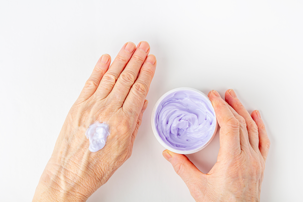 elderly woman creaming her hands