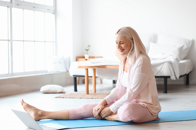 morning mature woman laptop practicing yoga