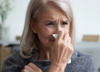 sick older woman blowing nose
