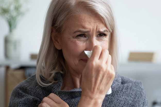 sick older woman blowing nose