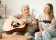 young woman her grandmother playing guitar