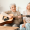young woman her grandmother playing guitar